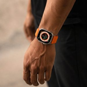 Model wearing Alpine Loop Band For Apple Watch in Orange Apple Watch band